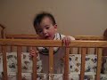 Maya standing in crib