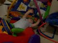 JJ falls over and lays down in his car toy