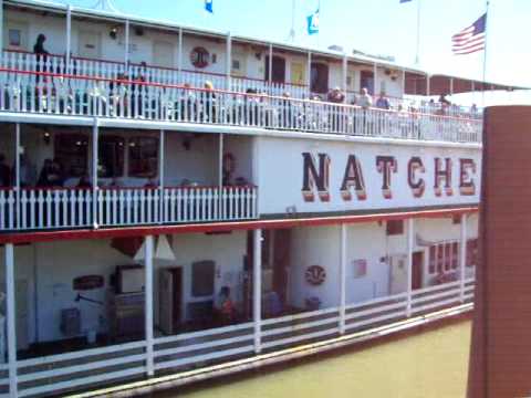 Steamboat - Engine room showing paddle wheel drive system, steam whistles blowing, and the docking procedure of the Natchez steam boat on the Mississippi River at the To...