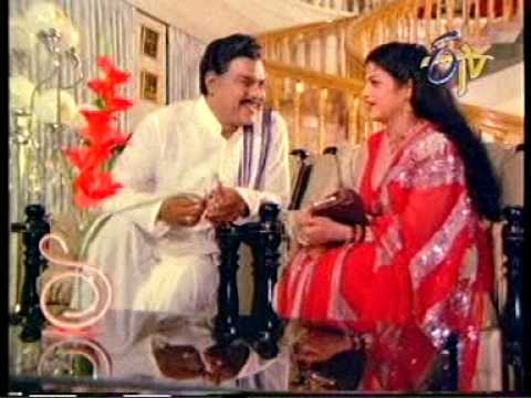 pallu drop - Jayamalini cheekily gives glimpses of her sexy deep cleavage in a sleeveless red blouse to a perverted old politician. The scene is from the movie Muddu Bidda.