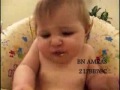 A cute baby enjoying what appears to be a tasteful fruit by performing a squeezing facial expression