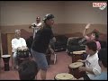 Screenshot of an activity in which a classroom containing persons with ID/DD alternate playing a drum at different speeds and volumes, cued by where the director places his hands.