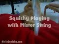Squishy Playing with Mister String on red pillow