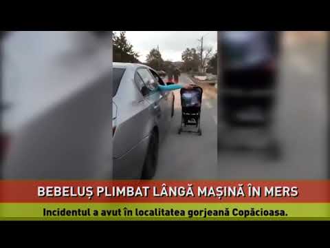 Bebeluş plimbat lângă o maşină în mers într-un cărucior împins de şofer