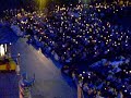 thousands of people singing the salve regina at the end of the daily torchlight rosary procession in lourdes, france