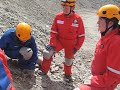 Students in an exercise doing a stretcher pass on large rubble pile.