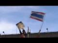 Thailand: Red shirt protesters dancing and waving Thai flag, standing on roof of police van