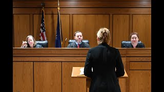student standing before a panel of judges in a courtroom