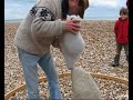 adrian gray demonstrating the delicate art of stone balancing, on the beach at lyme regis. hard to believe, and not as easy as it looks!