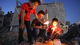 إضاءة الشموع وسط ركام المنازل المدمرة في مدينة بيت لاهيا في قطاع غزة | AFP