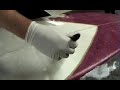 Building a surfboard; this video shows you how to laminate the fibreglass onto the bottom of a surfboard with resin.