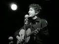 bob dylan - chimes of freedom 1964 live

far between finished sundown's an' midnight's broken toll
we ducked inside the doorway as thunder went crashing
as majestic bells of bolts struck shadows in the sounds
seeming to be the chimes of freedom flashing
flashing for the warriors whose strength is not to fight
flashing for the refugees on the unarmed road of flight
and for each an' ev'ry underdog soldier in the night
and we gazed upon the chimes of freedom flashing.

through the city's melting furnace, unexpectedly we watched
with faces hidden while the walls were tightening
as the echo of the wedding bells before the blowin' rain
dissolved into the bells of the lightning
tolling for the rebel, tolling for the rake
tolling for the luckless, the abandoned an' forsaked
tolling for the outcast, burnin' constantly at stake
and we gazed upon the chimes of freedom flashing.

through the mad mystic hammering of the wild ripping hail
the sky cracked its poems in naked wonder
that the clinging of the church bells blew far into the night
leaving only bells of lightning and its thunder
striking for the gentle, striking for the kind
striking for the guardians and protectors of the mind
and the unpawned painter behind beyond his rightful time
and we gazed upon the chimes of freedom flashing.

through the wild cathedral evening the rain unraveled tales
for the disrobed faceless forms of no position
tolling for the tongues with no place to bring their thoughts
all down in taken-for-granted situations
tolling for the deaf and blind, tolling for the mute
tolling for the mistreated, mateless mother, the mistitled prostitute
for the misdemeanor outlaw, chased and cheated by pursuit
and we gazed upon the chimes of freedom flashing.

tolling for the searching, on their speechless, seeking trail
for the lonesome-hearted lovers with too personal a tale
and for each unharmful, gentle soul misplaced inside a jail
and we gazed upon the chimes of freedom flashing.

starry-eyed and laughing as i recall when we were caught
trapped by no track of hours for they hanged suspended
as we listened one last time an' we watched with one last look
spellbound an' swallowed 'til the tolling ended
tolling for the aching ones whose wounds cannot be nursed
for the countless confused, accused, misused, strung-out ones and worse
and for every hung-up person in the whole wide universe
and we gazed upon the chimes of freedom flashing.