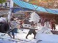 incredible footage of men in makassar, sulawesi indonesia carrying bags of sugar on their shoulders assembly line style onto a port.  you can also hear the mosques in the background. this is a very famous port town in indonesia.