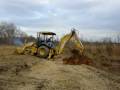 John Deere 310G backhoe digging up a stump