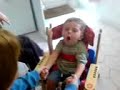 lewis in his giraffe chair, with jenna helping him to clap hands.