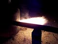 this is a basic waste oil burner.  we made this from an old a/c freon bottle we had laying around the house.  we then cut two holes into it, welded a pipe on the upper most hole and use it as the air inlet.  the bottom hole was left open as the exhaust.  

for the fuel, we took a half inch steel pipe and threaded it into the bottom backside of the bottle.  if you look closely in the video you can see it.  the fuel is any type of waste oil, peanut oil in this case.  we have the fuel in a rubbing alcohol bottle, which is connected to a ball valve, which is connected to the steel pipe on the bottom.

the burner is a bit complicated to get started because you need very high heat to start the oil fire.  the oil will only burn if it is hot enough to vaporize the oil.  to get it started we had to light some charcoal on the side and then place them into the bottle once they are glowing hot.  we then force the air in via an old vacuum that we rigged to blow air.  as the coals glow brighter, we slowly introduce the oil which starts to burn if it is hot enough.  the hotter the bottle gets, the better the oil burns.