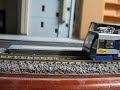 2007年10月頃に登場した蓄電池ハイブリッド路面電車「Hi-tram」（ハイトラム）のNゲージ鉄道模型です。実車は車内に積んだ蓄電池に充電して走ることができ、非電化区間でも走行できます。模型では充電時にパンタグラフを上げ下げする様子を再現するためにパンタグラフを操作できるようにしました。操作は走行用のパワーパック（コントローラー）で行います。モーターが回り出した瞬間の低速域と、動力台車のギヤの遊びを利用して、モーター起動から車両が動き出すまでの回転ロスを利用してパンタグラフ昇降を行う仕組みです。ギヤの遊びが無くなると車両が走り始めます。パンタグラフ搭載側に走らせるとパンタグラフを畳んだ状態で、パンタグラフの無い側へ走らせるとパンタグラフを上げた状態で走ります。実車は走行中にパンタグラフの昇降ができるそうですが、模型の方は走行用モーターを昇降に使うため停車中にしか操作できません。DCCを使って別回路を作れば独立操作できるかも。