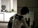 肩から提げたリズムボックスの音楽のリズムに乗って絵を描くパフォーマンスをする東京都庁前で都庁舎を描く