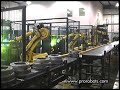The robot picks parts from the infeed conveyor and delivers them to stationary tandem MIG torches rotating parts during the weld process without welding fixtures, then places the part on a outfeed conveyor.