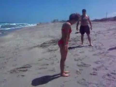 Chica en bikini practica voltereta y come arena