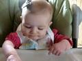 Elizabeth eating puffs in highchair
