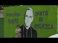 woman in front of Romero mural