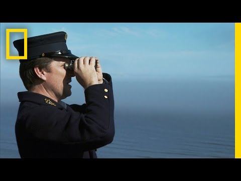 капитан корабля смотрит в бинокль на волнах