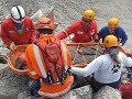 Students in an exercise doing a stretcher pass on large rubble pile.
