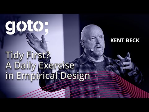Man giving a conference talk. Bald, plaid shirt, slightly overweight, old-ish, looks like a typical American programmer.