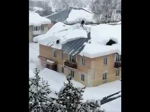 Dwóch specjalistów od odśnieżania dachu w akcji