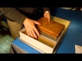 The spine strip is covered, the box is assembled with a standing press. Smaller boxes can be finished, preferably, in nipping presses but also with weights (passive pressure). The aggressive pressure of a press will insure a tighter bond and will also squeeze any trapped air out of the space between the case and a tray. In any case, don't leave the box under aggressive pressure longer than 10-15 minutes, the fabric may become compressed and shiny where the pressure is greatest.