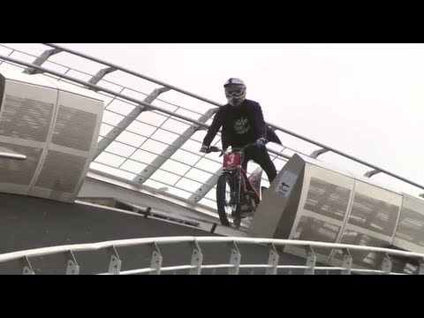 Freestyle trials rider crosses bridge span Thumbnail of Video