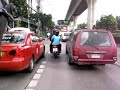 This is my morning journey to the Skytrain station. I am taking a motorcycle taxi, which is the fastest way to get through this traffic. Its a thrill ride. In this clip you can see, (1) A cop directing traffic. (2) Taxi motor bikes, they wear orange jackets. (3) Heavy traffic many busses, cars/trucks/taxi's. (4) Driver of bike wears mask as protection fumes. (5) Police pull-over motorcycle. (6) Beggar I give him a coin. (7) Lottery slaes people, one of them is blind. (8) Armed cop, they all carry guns here.