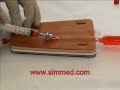 IV Cannulation (Catheterization) being practised on the SimMed V-IV pad. The student accesses the artificial vein and flushes the cannula with saline.