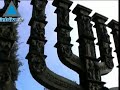 The Menorah, which stands in the area in front of the Knesset gates, was designed by the Jewish English sculptor Benno Elkan, and was donated to the Knesset by the members of the British Parliament on April 15, 1956. The subjects depicted on its reliefs are drawn from the Jewish tradition. The nation is represented as a single whole, which is made up of many links. The glorious spiritual creations of the nation, its influential personalities and the fateful events that befell it, are depicted on the Menorah. The scenes on the Menorah are scattered with no chronological order, where every relief on a branch on the left side is complemented by one on a branch on the right side. The central branch presents th