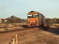 Two NRs pull a mixed empty steel, general freight and car train over the Hospital Road LX and past the workshops in Port Augusta, late in the afternoon