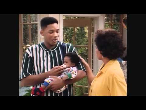 A screenshot of the Fresh Prince of Bel-Air with Will Smith in a black and white striped shirt holding a small baby and talking to a woman with a yellow shirt and dark hair