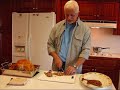 In this video, Betty's husband, Rick carves the Thanksgiving turkey. The turkey has just been roasted and allowed to rest 15 or 20 minutes, Rick uses a freshly sharpened knife for the carving procedure. Rick first separates the legs from the turkey, and cuts the drumstick from the thigh. He paces the turkek drumsticks on a serving platter, and slices the remaining dark meat, cutting across the grain. He then makes a cut down the center of the breast, and slices the white meat, cutting across the grain, and placing these on the platter in a pleasing arrangement. Any leftover pieces are saved for other purposes. The platter of turkey is garnished with some orange wedges and parsley.