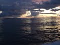 Port side view of a beautiful sunset and rain in the distance, as the Mustin patrols the South China Sea.
