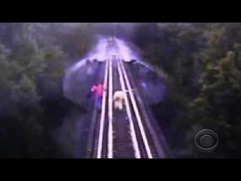 this morning - A camera mounted on a train engine captured the dramatic escape of two women who were caught on the tracks of a railway bridge. The women made a split-second decision to dive between the tracks...