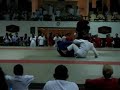 This is a classic BJJ versus Judo Superfight - Hasan Mussa (white gi - Judo) vs Zaid Mirza (BJJ).  The lessons from this match are that you cannot run off the mat to escape a submission and then expect a referee to re-start a match in exactly the same position.  Hasan was lucky that he did not get disqualified for running out of the match area as there was at least a 3 foot drop off the mats and if they had fallen off, someone would have been hurt - they only stayed on the platform with the referee balancing precariously at the edge.  The referee would have been justified in disqualifying Mussa, but evened the playing field with the way he re-started the players.  Watch the way at the end that the referee yells at the complaining spectators that they know nothing about JJ - effectively offering a confrontation.  Wisely no-one took him up on that.