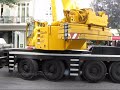 Kran hebt PKW-Anhänger auf ein Dach.