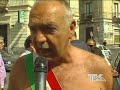 Fascia tricolore su torso nudo, con indosso soltanto boxer bianchi elasticizzati, calzini dello stesso colore e scarpe scure: è il 