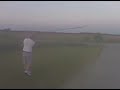 John hitting a golf ball @ a sign.