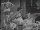 a chorus of co-eds, including toby wing, betty grable perform a water formation production number with eddie cantor looking on. from 1932 .