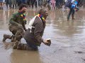 A crowd waits and watches as two hapless drunkards fall into the mud-hole trap next to the Pyramid Stage at Glastonbury Festival. Pure evil