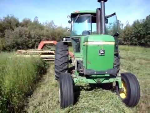 4430 - John Deere 4430 and New Holland 499 hydroswing Haybine mowing hay in the summer of 2011 in the Peace Country of Northern Alberta Canada. Old equipment still ...