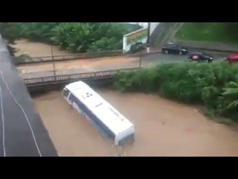 Ônibus é arrastado pela chuva, cai no rio e bate em ponte