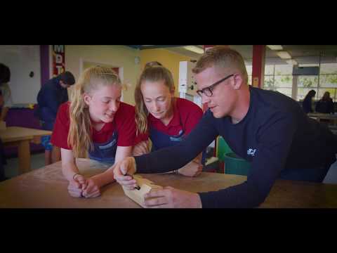 Tyler Richardson instructing two students on woodwork technique