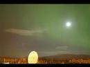 A fast flow from the west over the hills gives rise to lee waves with clouds forming and dissolving as the air is forced up and down when passing the wave structures. The sky conveniently clears temporarily as an auroral substorm takes place. The moon (half) adds to the scenario.
